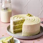 Vegan pistachio cake sliced on a table with pistachio crumbs