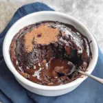 Rich and gooey chocolate pudding cake with a soft, fudgy sauce layer, served warm in a white ramekin with a spoon the perfect self-saucing dessert.
