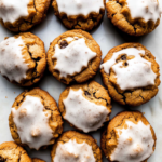 Soft pumpkin cookies topped with sweet vanilla glaze arranged on a baking surface