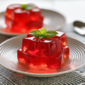 Red gelatin trick recipe cubes topped with fresh mint on a plate